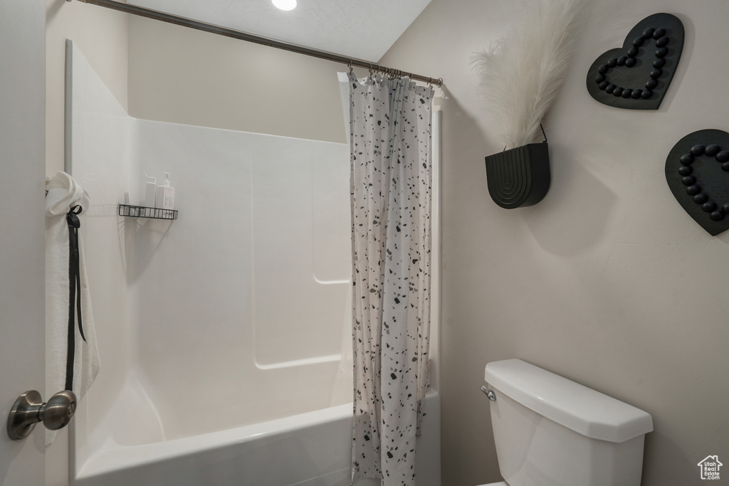Full bath featuring shower / bath combo with shower curtain and toilet