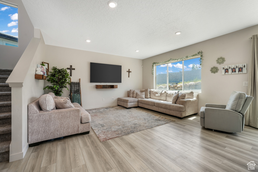 Living area with stairs, light wood-style floors, recessed lighting, and a textured ceiling