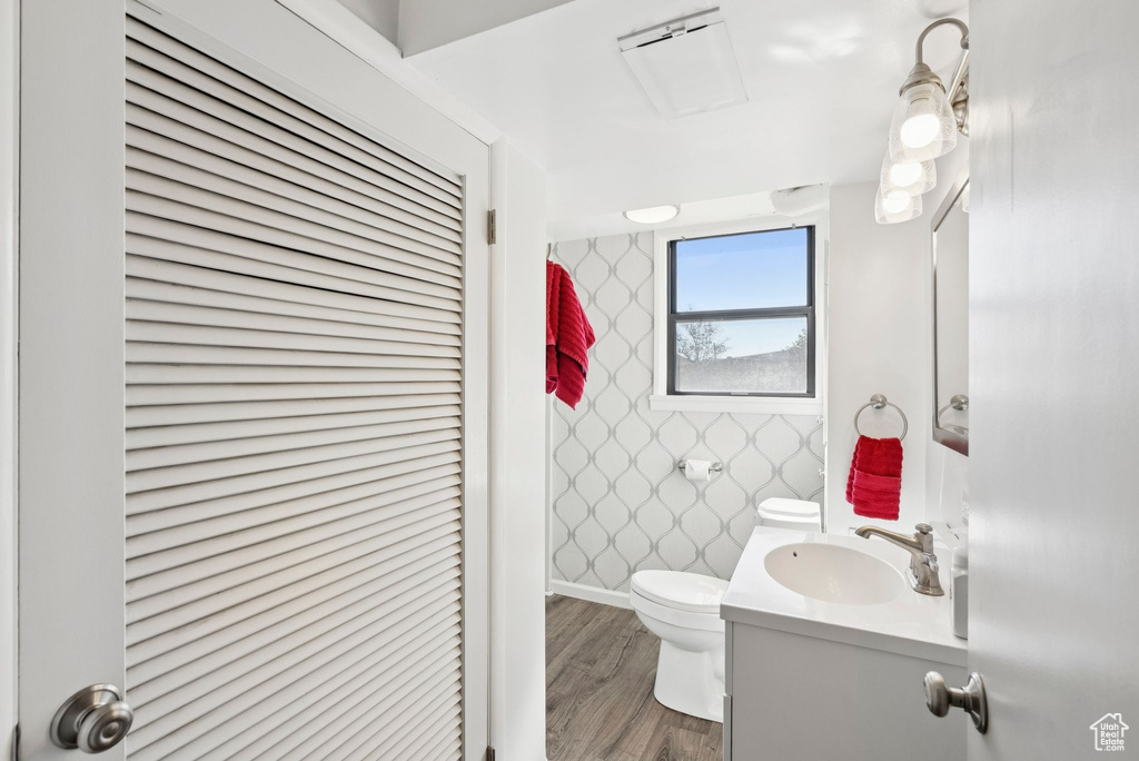 Bathroom with vanity, wood finished floors, and wallpapered walls