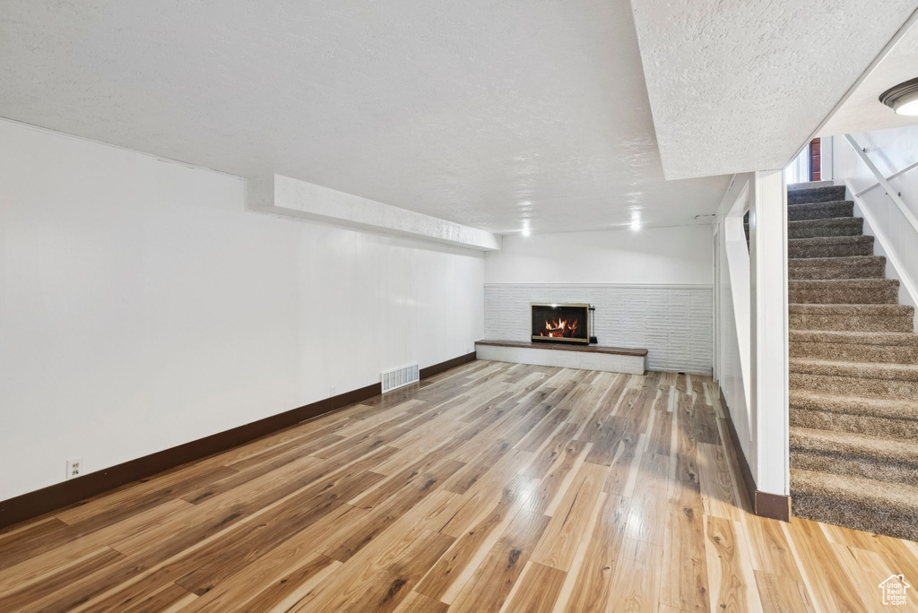 Unfurnished living room featuring wood finished floors, stairs, and a fireplace