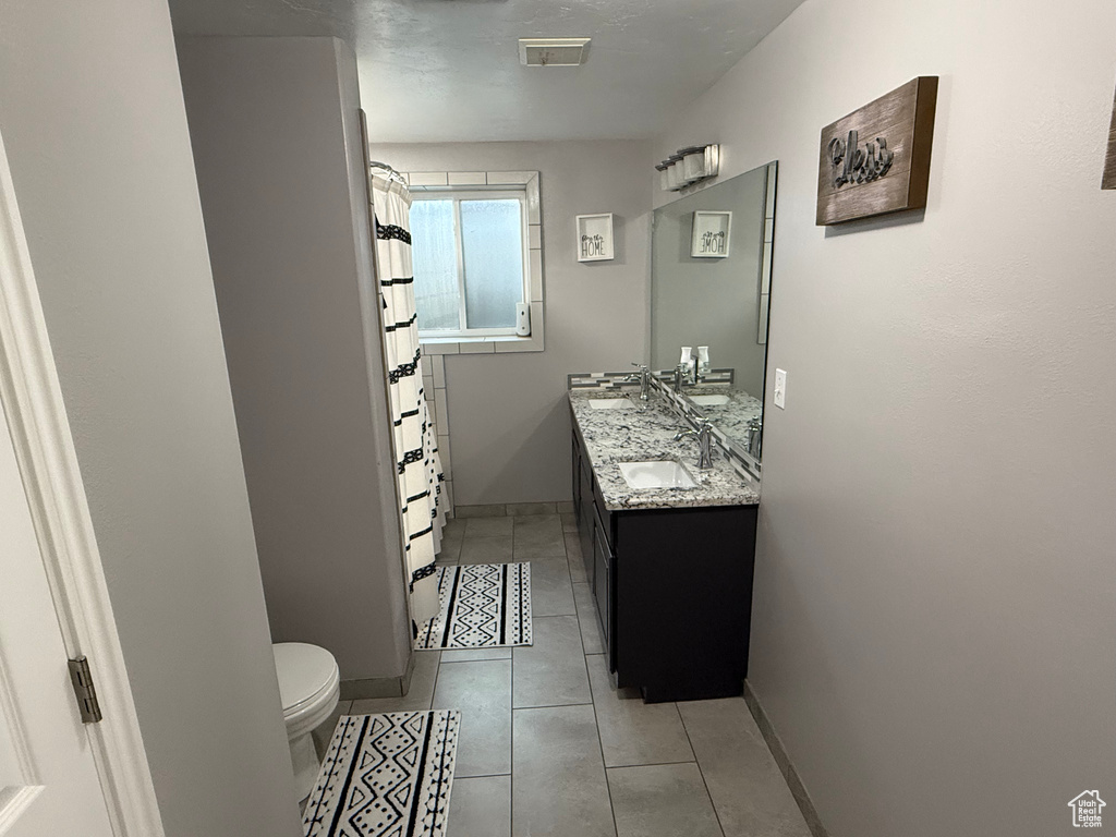 Full bathroom featuring double vanity, tile patterned flooring, and curtained shower