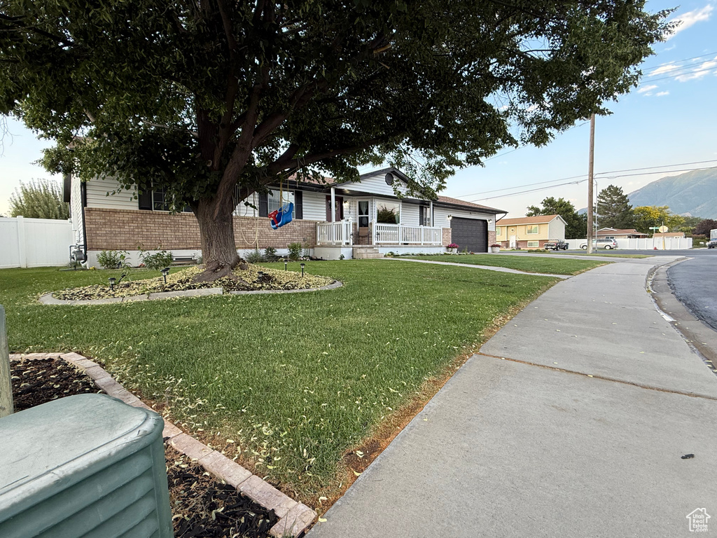 Ranch-style home with brick siding, an attached garage, covered porch, driveway, and a mountain view