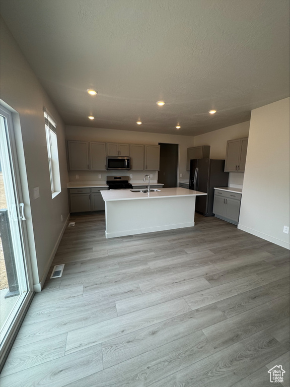 Kitchen with gray cabinetry, freestanding refrigerator, light countertops, electric stove, and recessed lighting