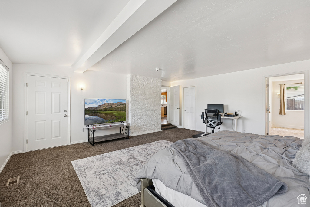 Carpeted bedroom with beam ceiling and ensuite bathroom