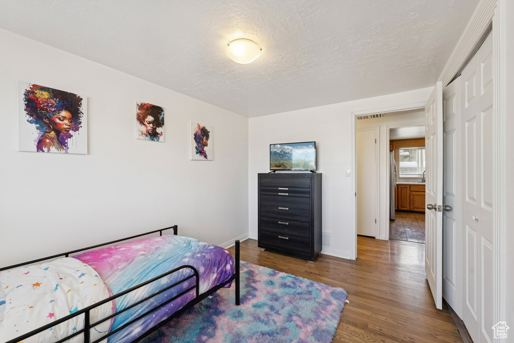 Bedroom with wood finished floors, a closet, and a textured ceiling