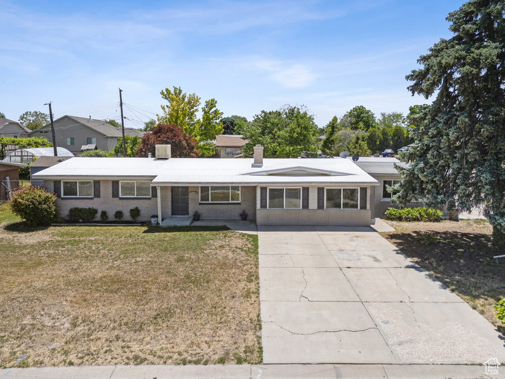 Ranch-style home with driveway, a front lawn, a chimney, and brick siding