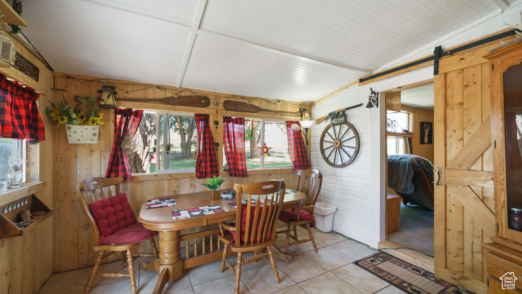 Dining room featuring wooden walls, a barn door, and tile patterned flooring