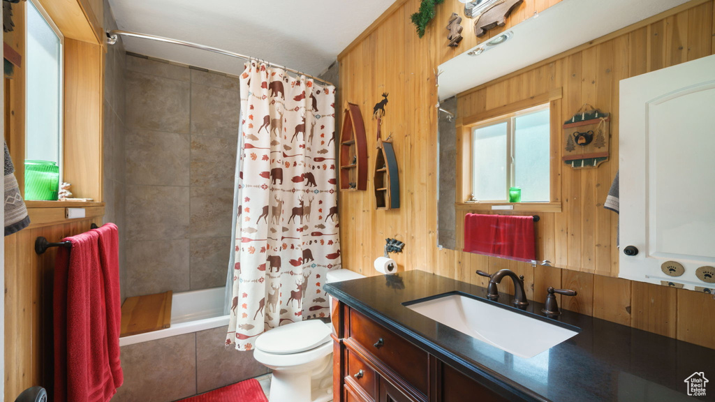 Bathroom with vanity, a tile shower, and wooden walls