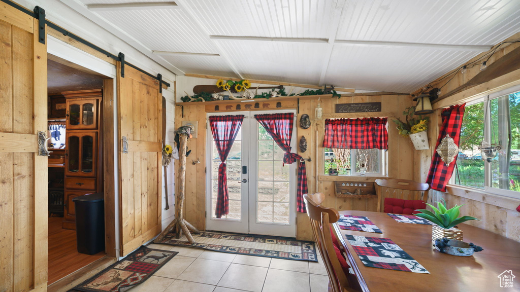 Sunroom with a barn door, lofted ceiling, and french doors