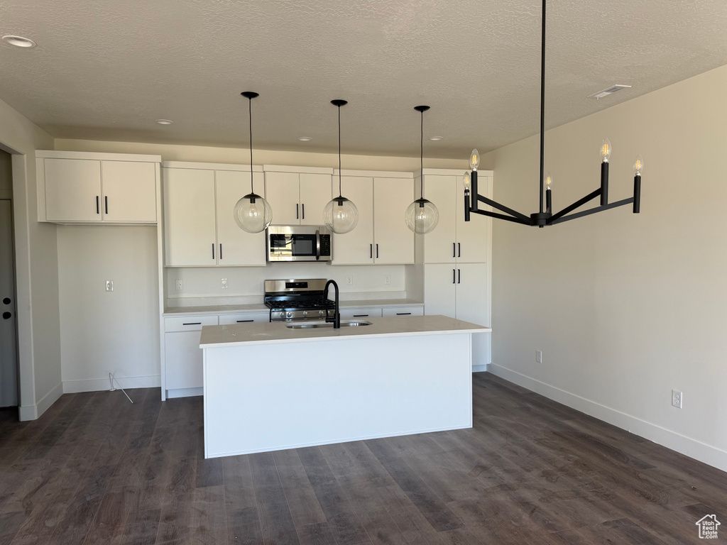 Kitchen with appliances with stainless steel finishes, white cabinets, an island with sink, dark wood-type flooring, and recessed lighting