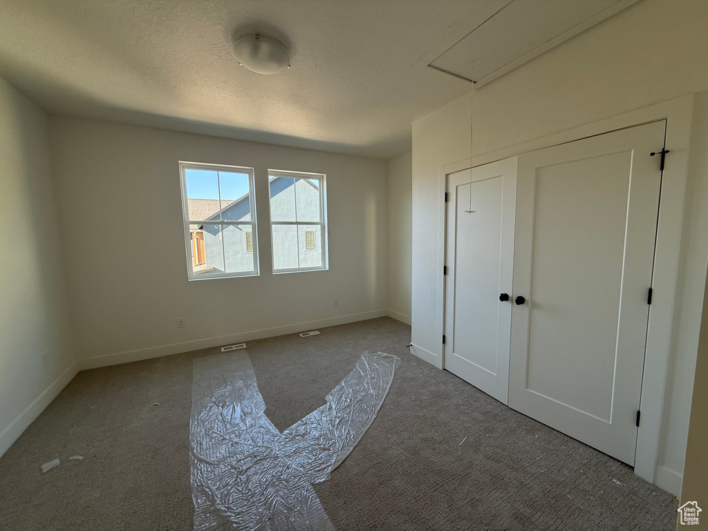 Unfurnished bedroom with attic access and carpet flooring