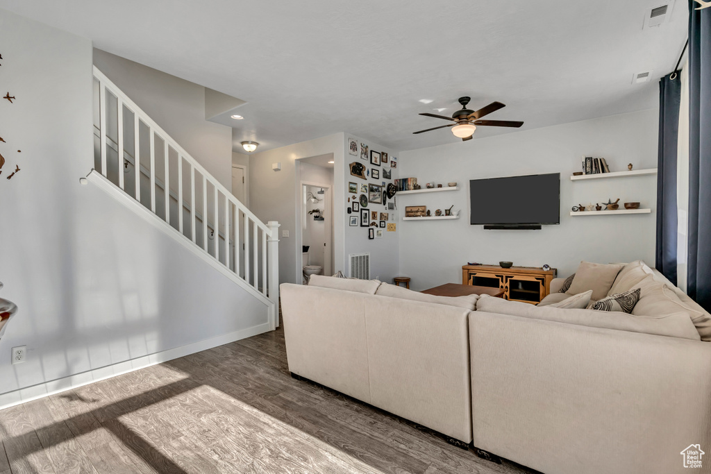 Living area with wood finished floors, a ceiling fan, stairs, and recessed lighting