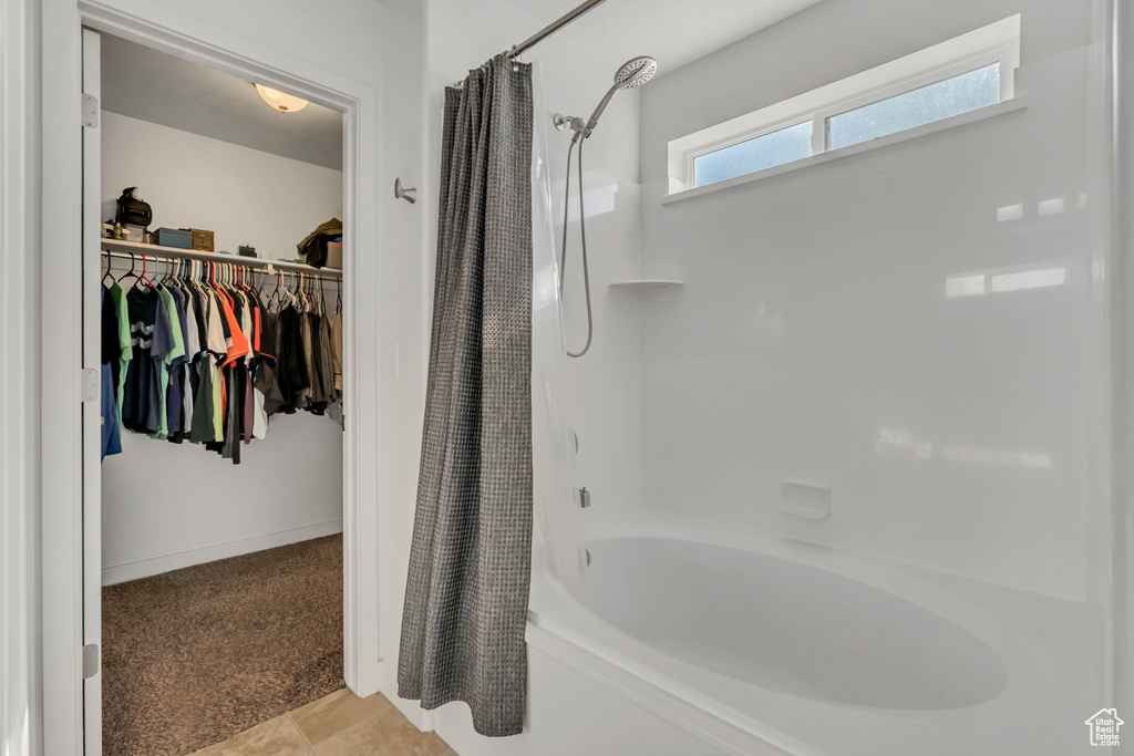 Full bathroom with shower / bathtub combination with curtain and a walk in closet