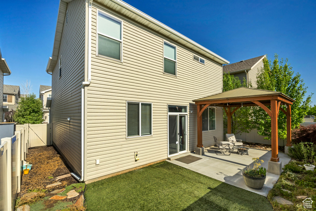 Rear view of house with a gazebo, a fenced backyard, and a patio area