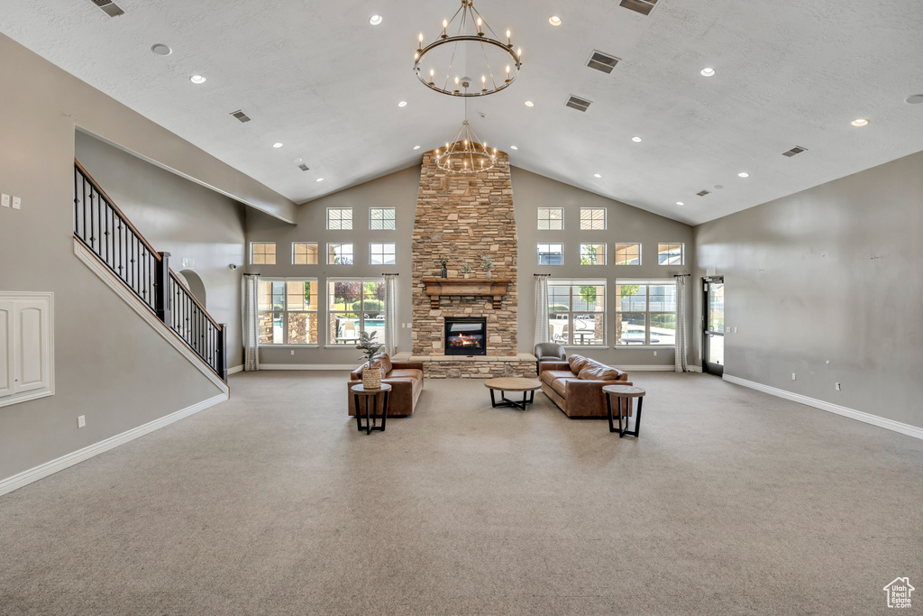 Carpeted living area featuring a chandelier, a fireplace, high vaulted ceiling, and recessed lighting
