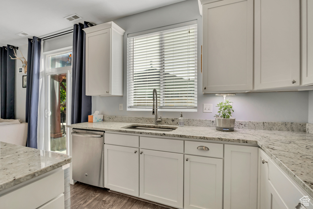 Kitchen featuring stainless steel dishwasher, white cabinetry, wood finished floors, and light stone countertops
