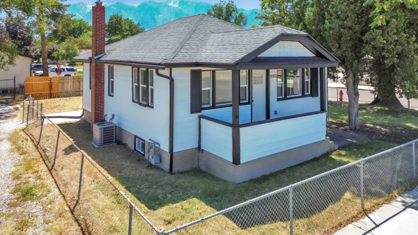 View of front of house with a chimney, a fenced backyard, a shingled roof, and a mountain view