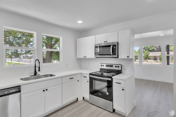Kitchen with appliances with stainless steel finishes, light wood-style flooring, plenty of natural light, light countertops, and recessed lighting