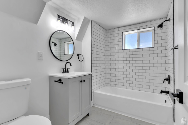 Full bathroom with vanity, shower / bathtub combination, and a textured ceiling