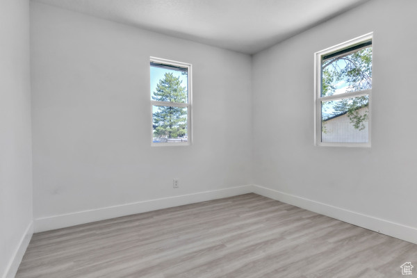 Spare room featuring baseboards and light wood finished floors