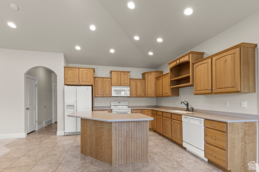 Kitchen featuring white appliances, arched walkways, a kitchen island, light countertops, and high vaulted ceiling