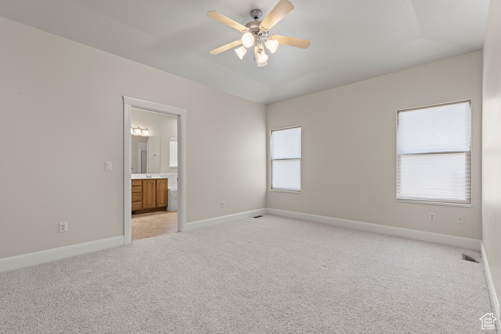 Unfurnished bedroom with light carpet, vaulted ceiling, connected bathroom, and a ceiling fan