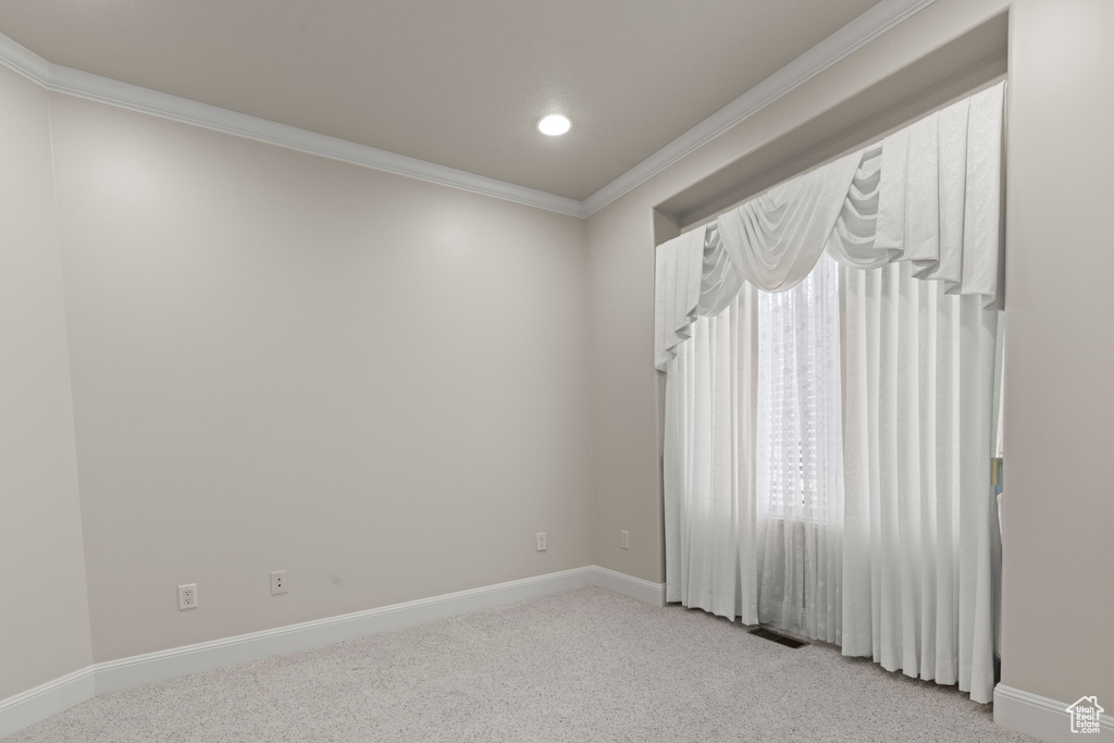Empty room with light carpet, crown molding, and recessed lighting