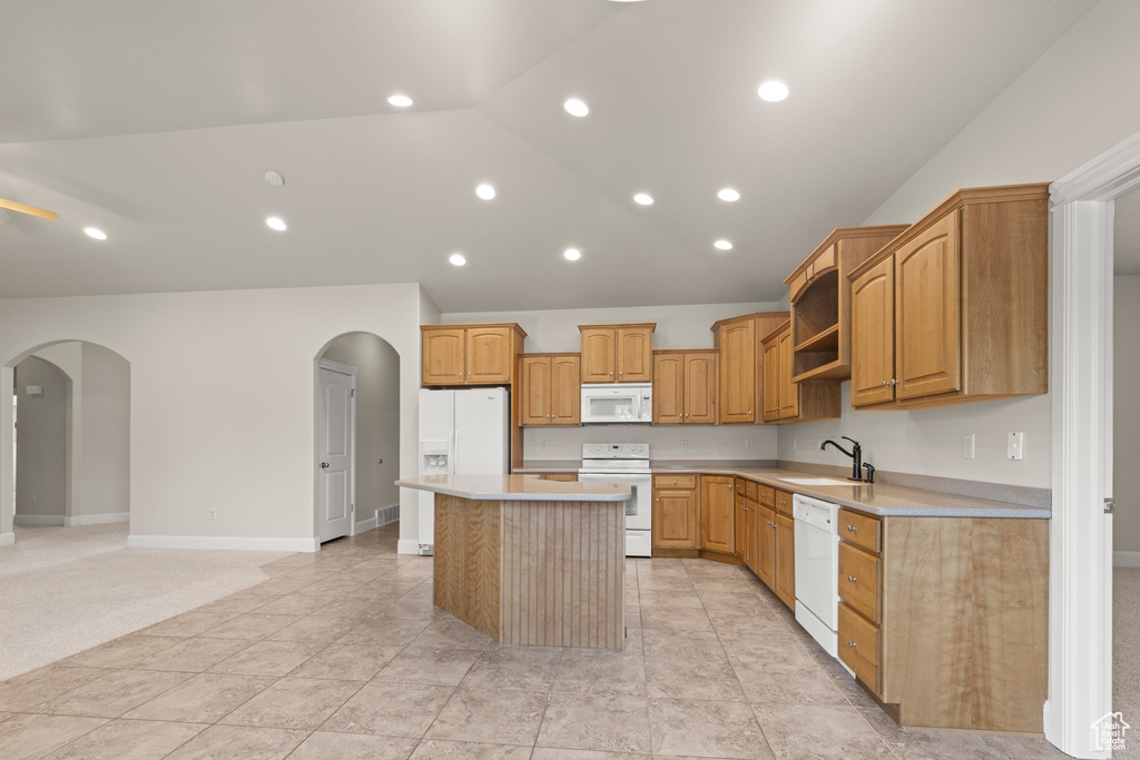 Kitchen featuring white appliances, arched walkways, a center island, light countertops, and open shelves
