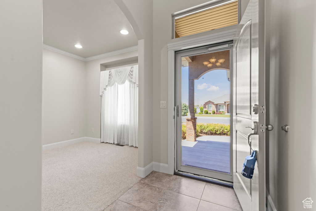 Foyer entrance with ornamental molding, arched walkways, light colored carpet, light tile patterned floors, and recessed lighting