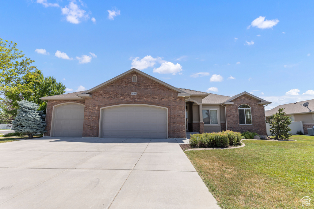 Single story home featuring a garage, brick siding, a front yard, and concrete driveway