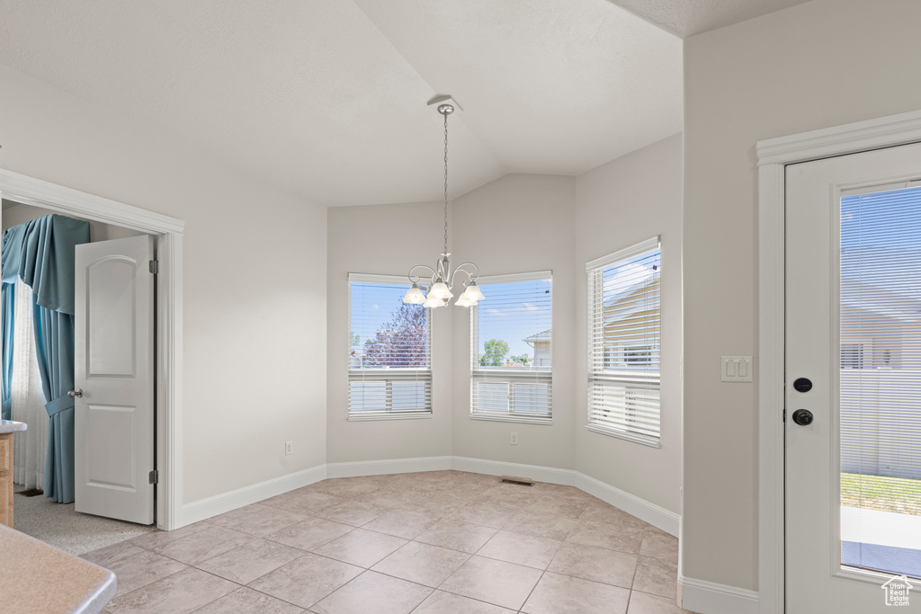 Unfurnished dining area featuring a chandelier, lofted ceiling, and light tile patterned floors