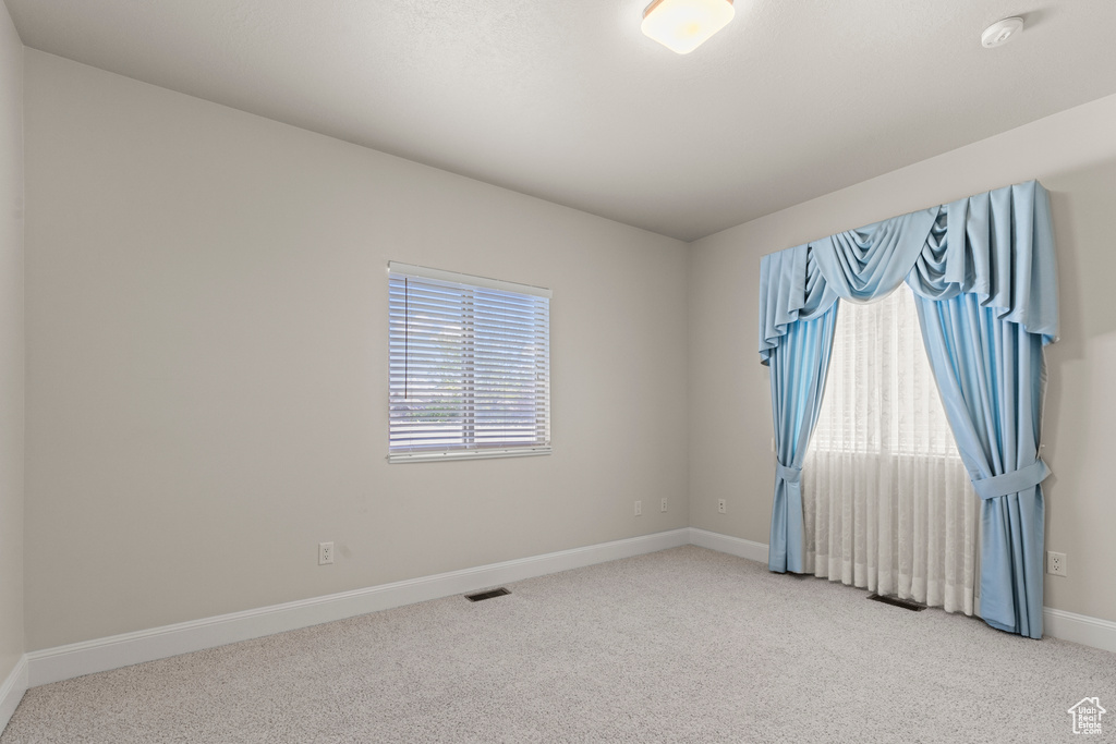 Carpeted empty room featuring baseboards and a smoke detector