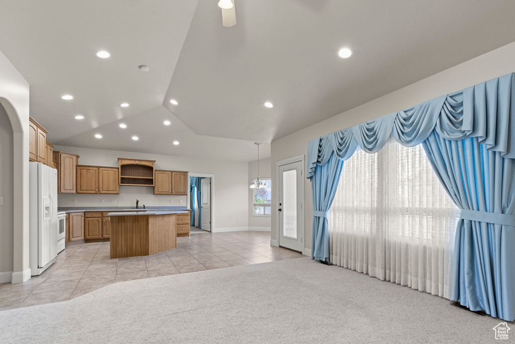 Kitchen featuring white fridge with ice dispenser, open shelves, a kitchen island, light tile patterned floors, and light colored carpet
