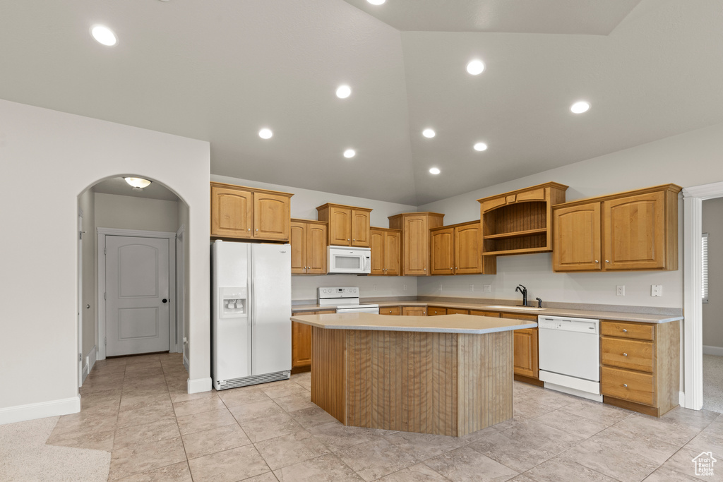 Kitchen featuring white appliances, arched walkways, a center island, light countertops, and open shelves