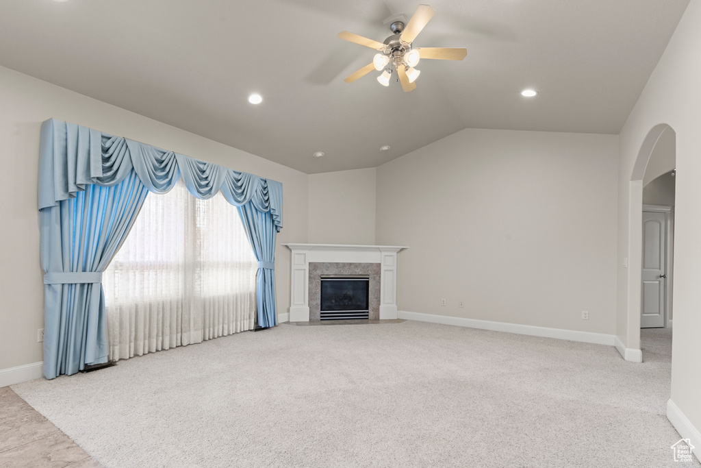 Unfurnished living room with arched walkways, carpet floors, ceiling fan, recessed lighting, and a fireplace