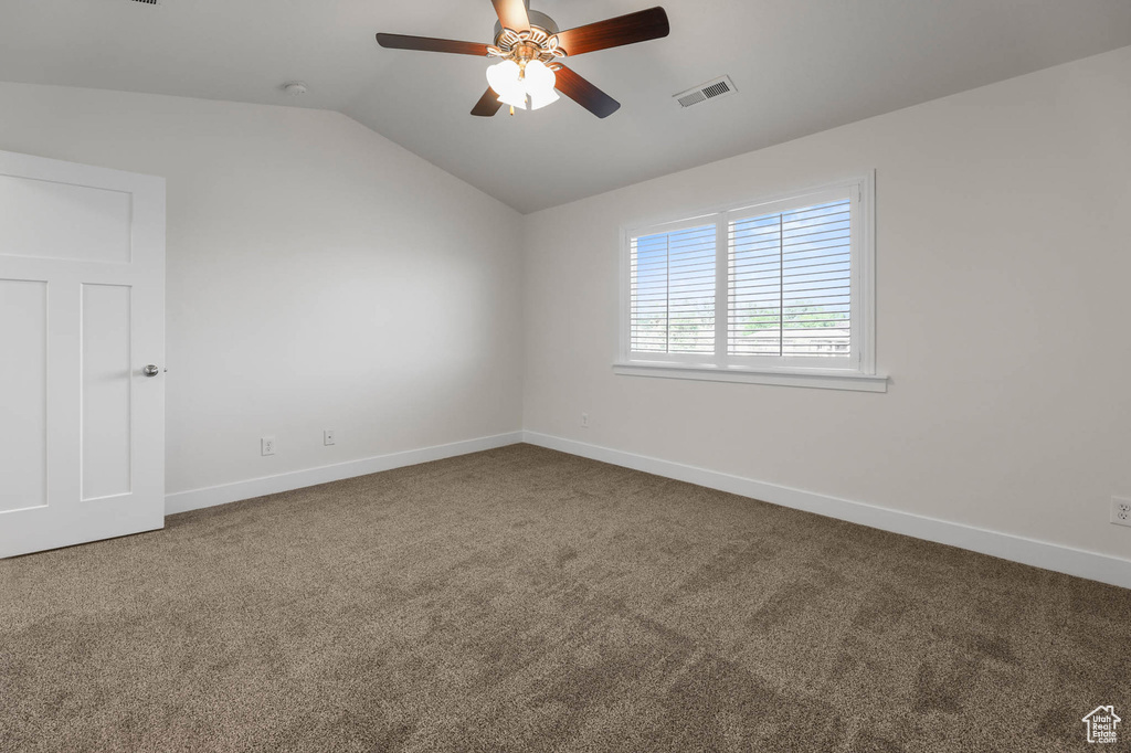 Carpeted spare room with lofted ceiling and a ceiling fan