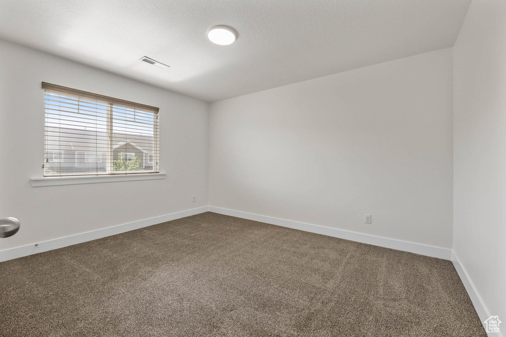 Spare room with dark colored carpet and baseboards