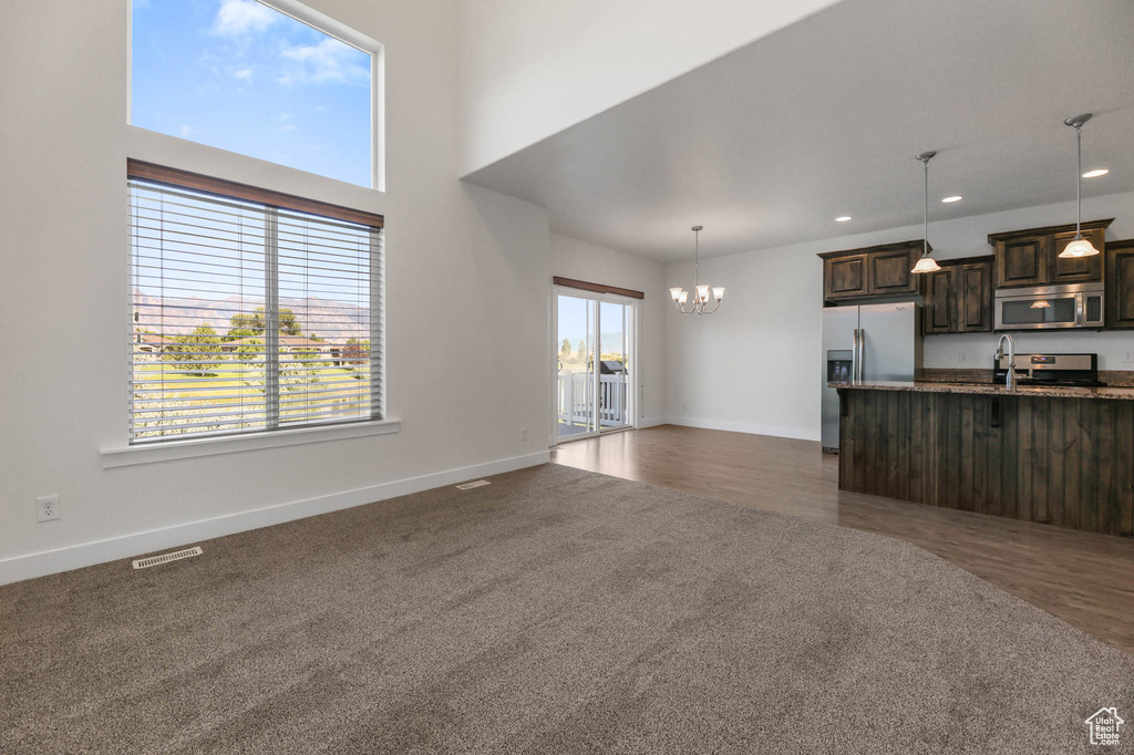 Unfurnished living room featuring a chandelier, dark colored carpet, and recessed lighting