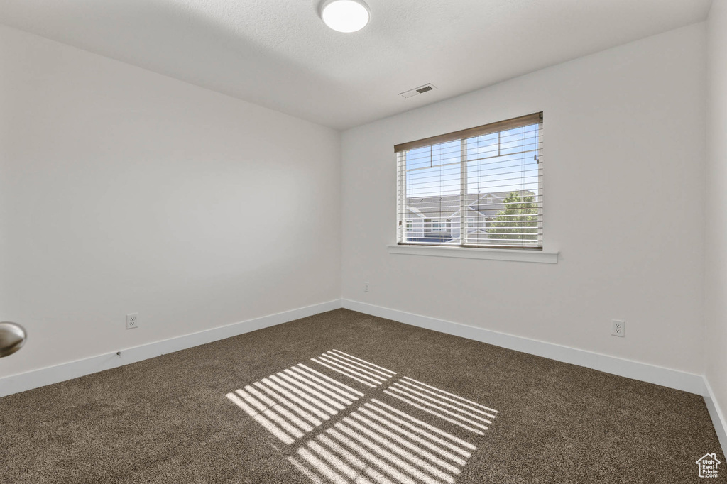 Empty room with dark colored carpet and baseboards
