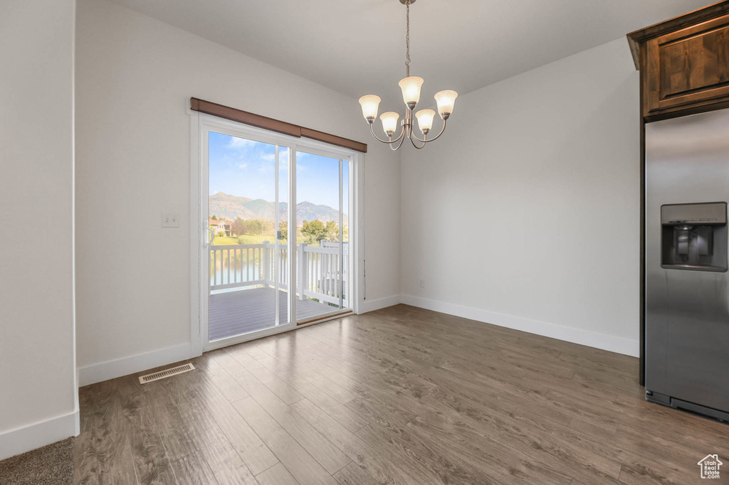Unfurnished dining area with a chandelier, wood finished floors, and a water view