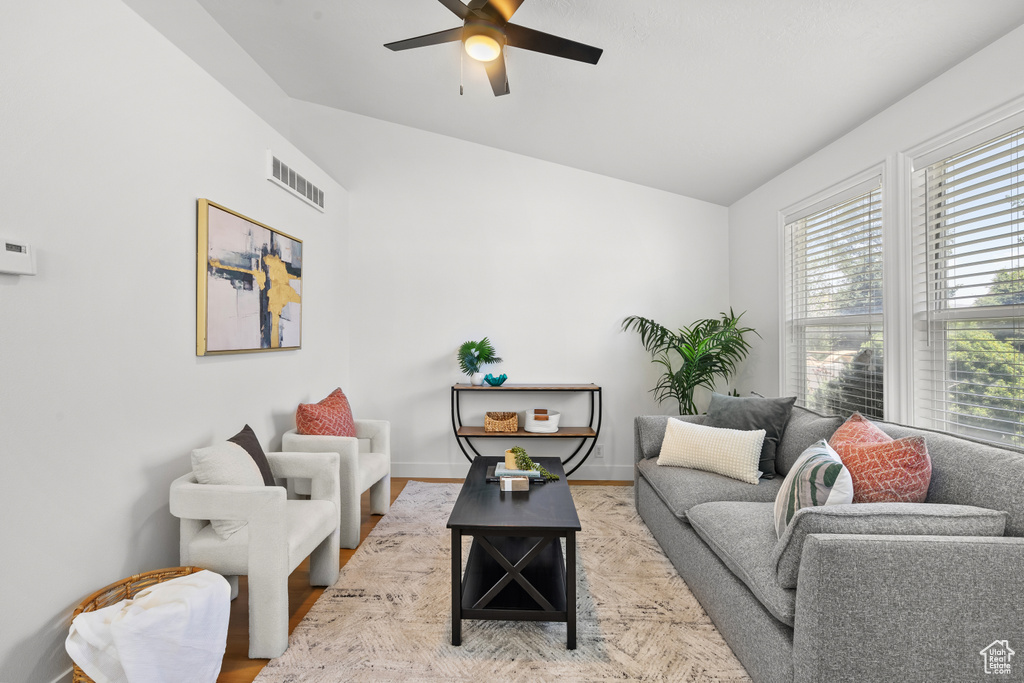 Living room with vaulted ceiling, a ceiling fan, and wood finished floors