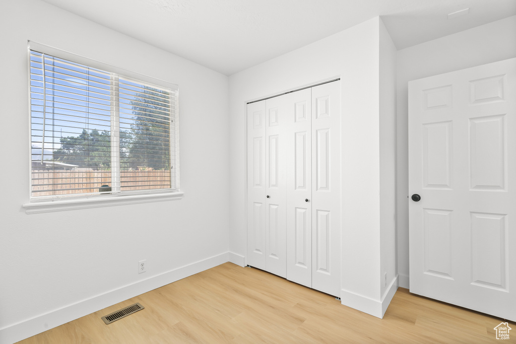 Unfurnished bedroom with light wood-type flooring and a closet