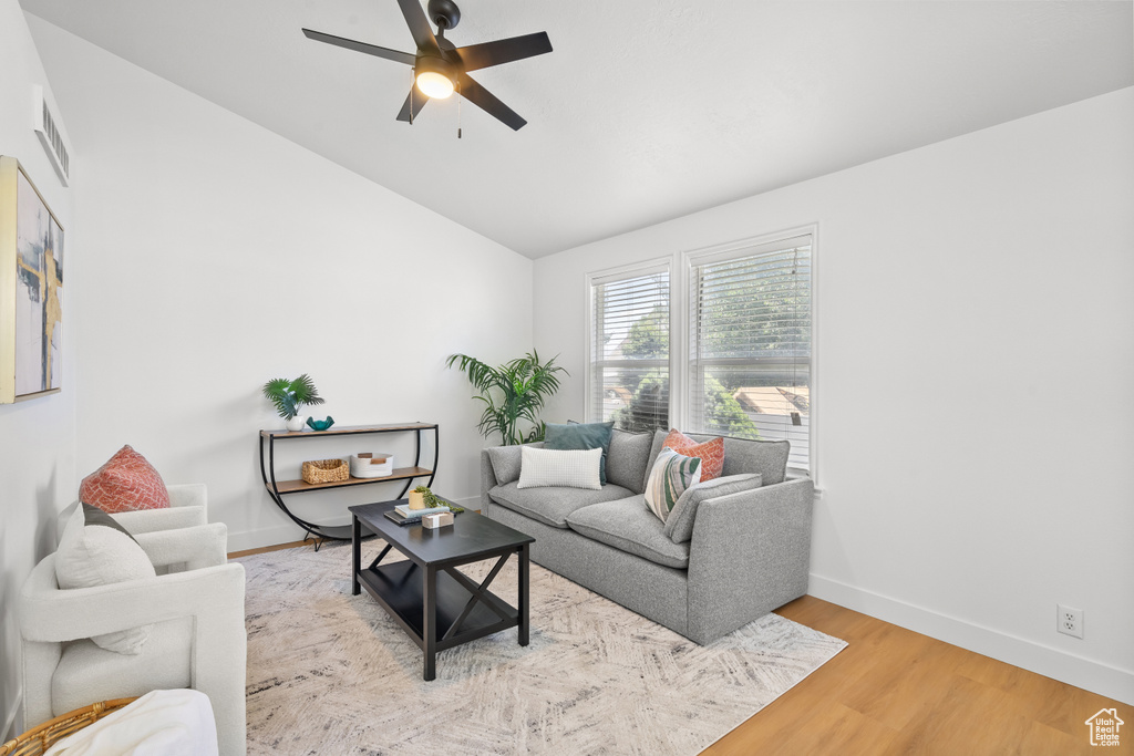 Living room featuring ceiling fan, lofted ceiling, and light wood-type flooring