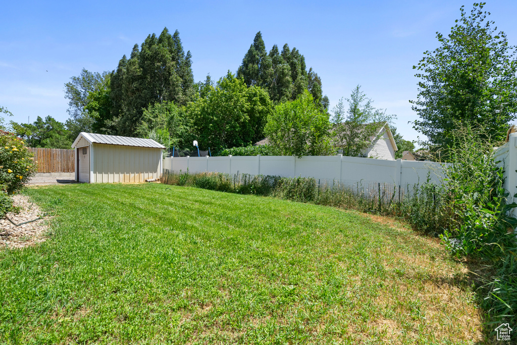 Fenced backyard featuring a storage shed