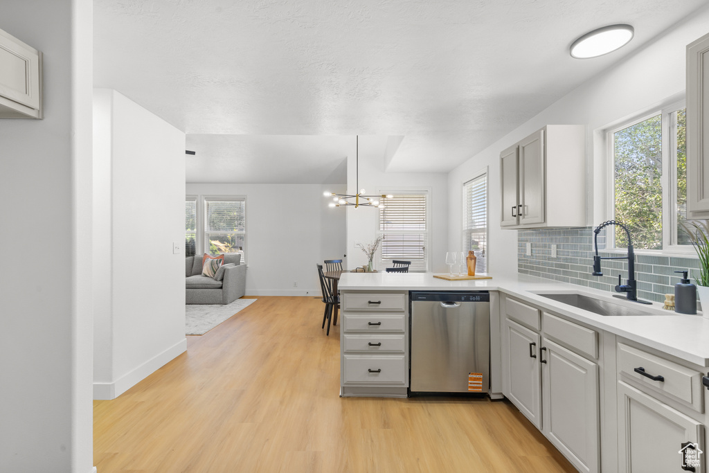 Kitchen featuring dishwasher, light wood finished floors, a peninsula, light countertops, and open floor plan