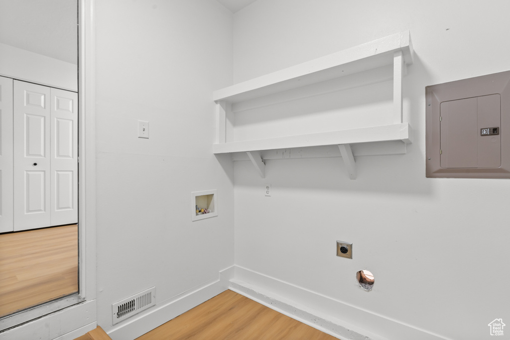 Washroom with electric panel, hookup for a washing machine, wood finished floors, and hookup for an electric dryer