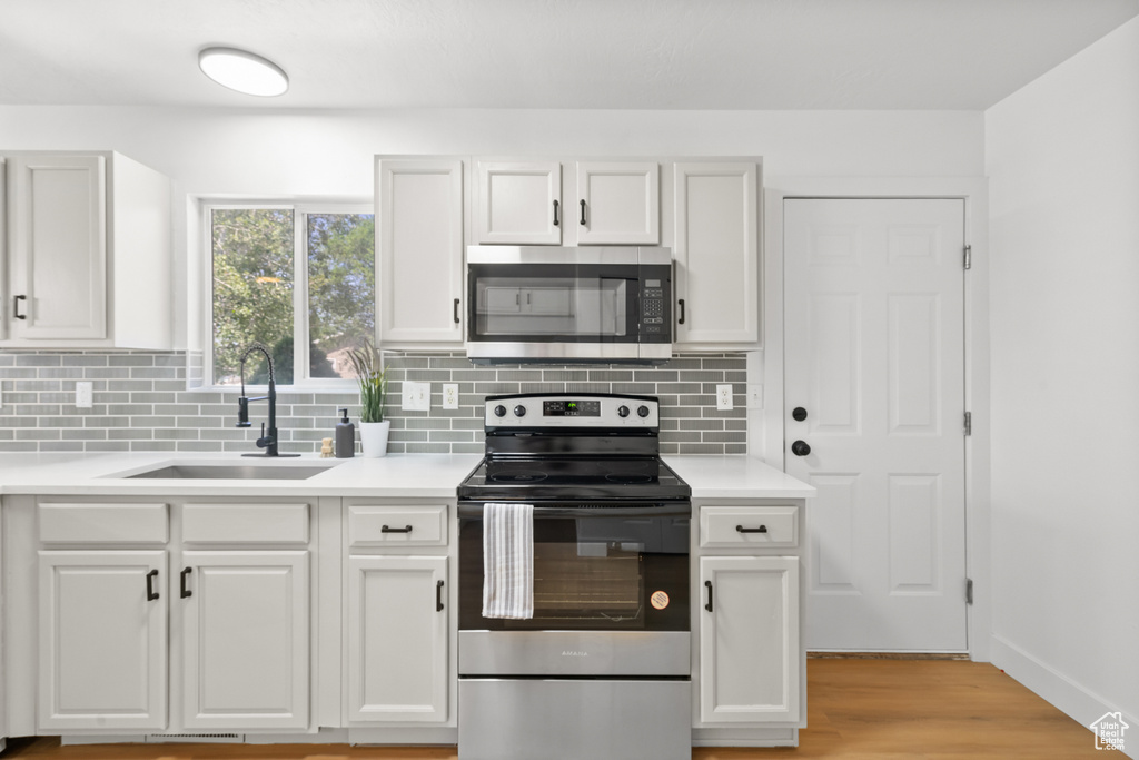 Kitchen featuring stainless steel appliances, backsplash, and white cabinets