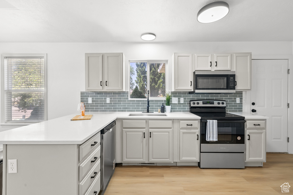 Kitchen with stainless steel appliances, a peninsula, light countertops, and tasteful backsplash