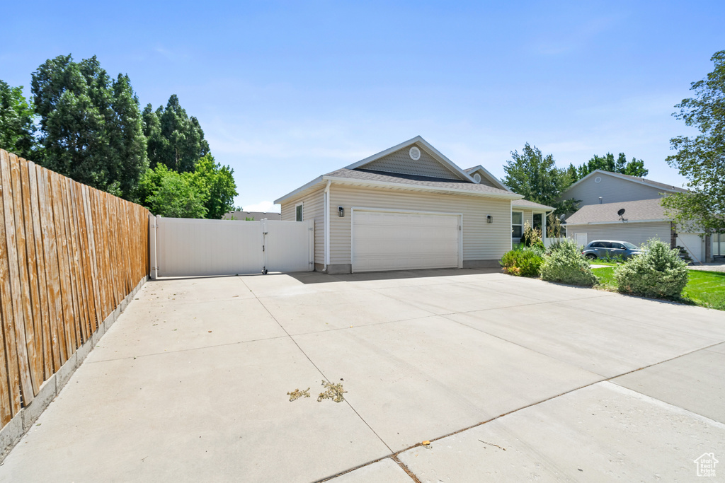 View of front of home with driveway, a gate, and an attached garage