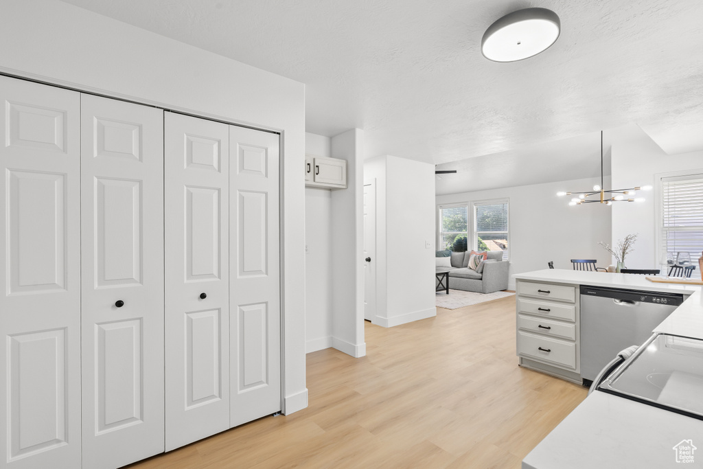 Kitchen with dishwasher, light wood-type flooring, open floor plan, and light countertops